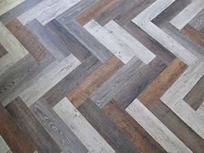 Luxury vinyl planks of various colors arranged in a herringbone pattern make for a stylish, waterproof flooring option for modern homes.