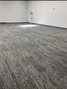 A large room in an office building with a freshly installed gray carpet.
