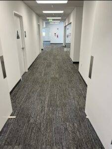 A hallway in an office building with brand new gray carpeting installed by Slaughterbeck Floors.